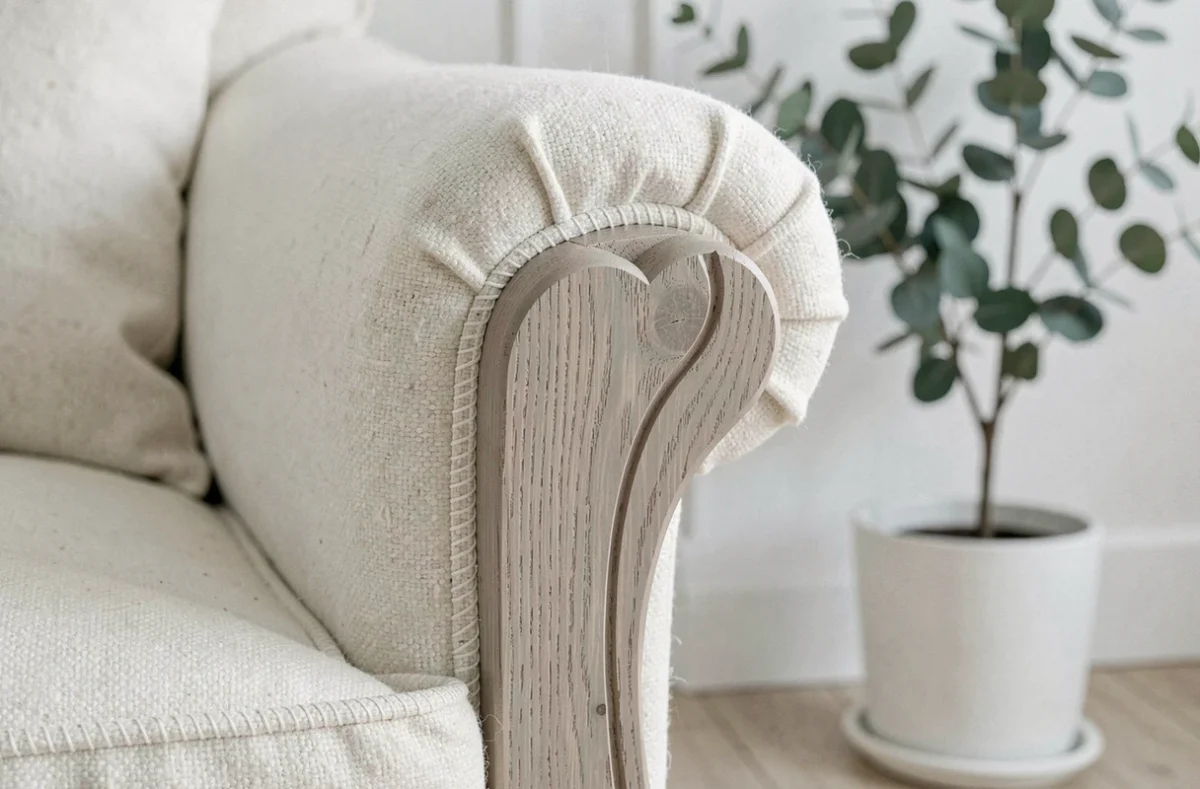 Détail gros plan accoudoir et pied bois d'un fauteuil Voltaire rénové style scandinave en tissu laine ivoire