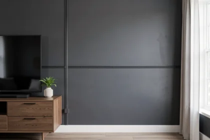 Goulotte électrique anthracite posée le long d'un mur gris foncé